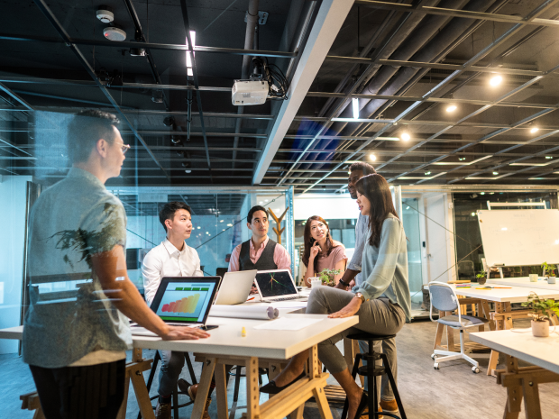 A group of colleagues gathered around a table in an open office.